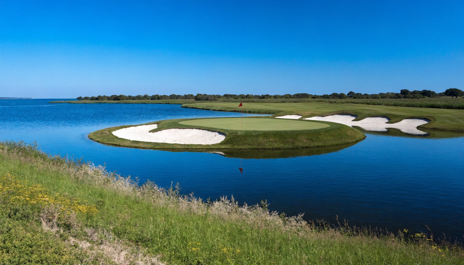 An island green in blue water on a clear day